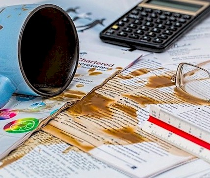 Picture of a desk with documents that have been covered with liquid from an overturned coffee cup.