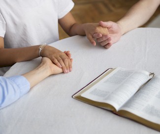 Three people holding hands whilst praying